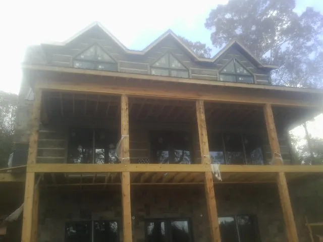 Dormers and porch framing on a large log home under construction — Roof Coating work by our crew in Lesterville