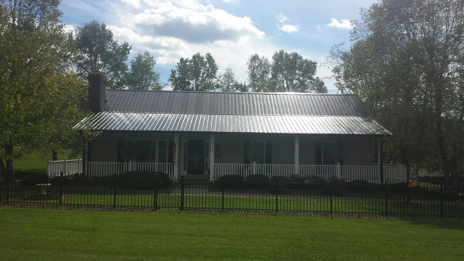 Gray metal roof on a brick ranch with a full width front porch — Gutter Guard Installation work by our crew in Lesterville