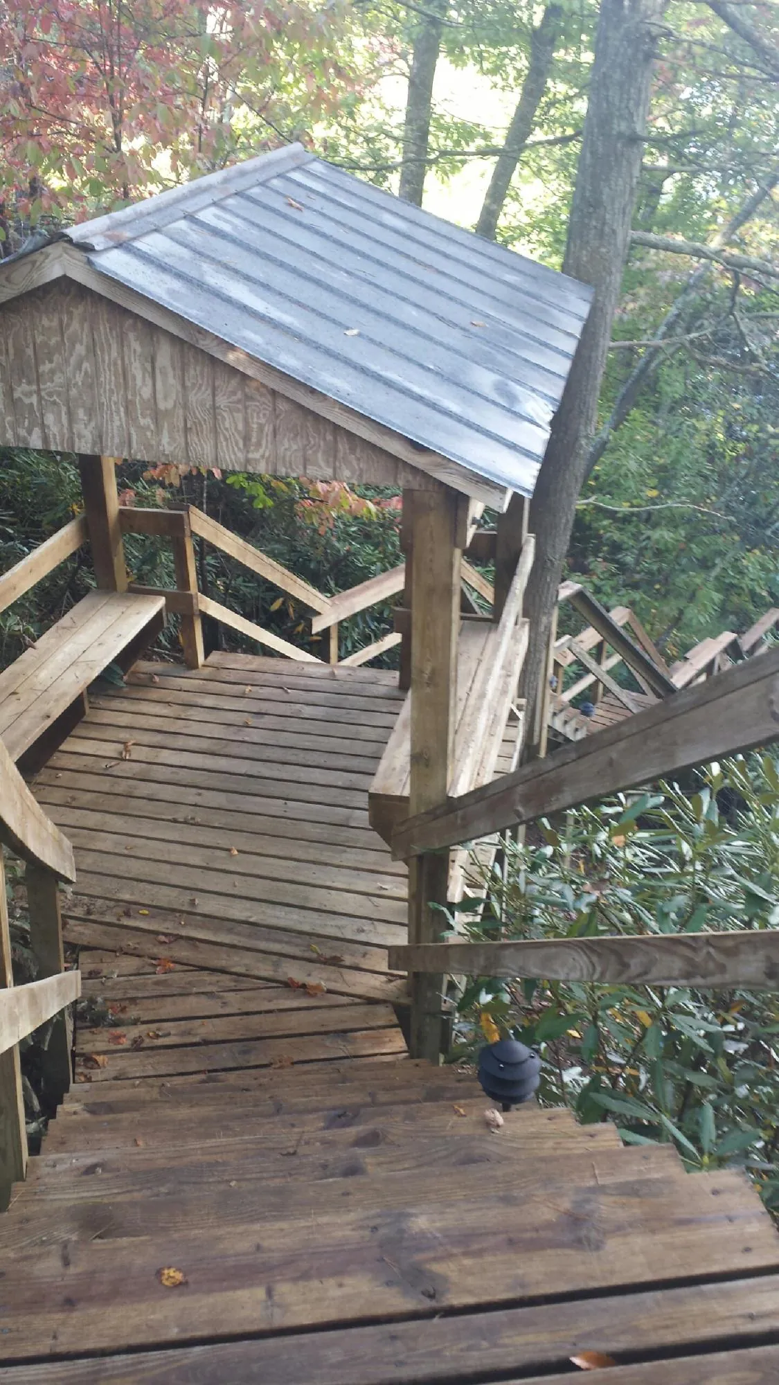 Metal roofed shelter over wooden steps on a wooded walkway — Skylight Repair & Installation work by our crew in Lesterville
