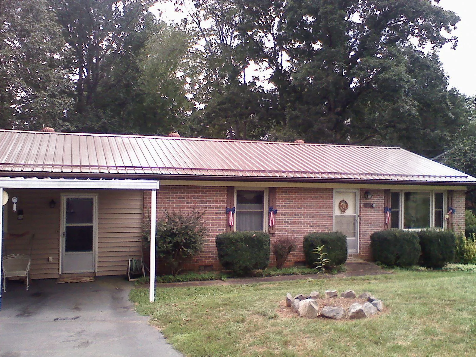 Bronze metal roof and carport on a brick ranch home — Roof Repair work by our crew in Lesterville