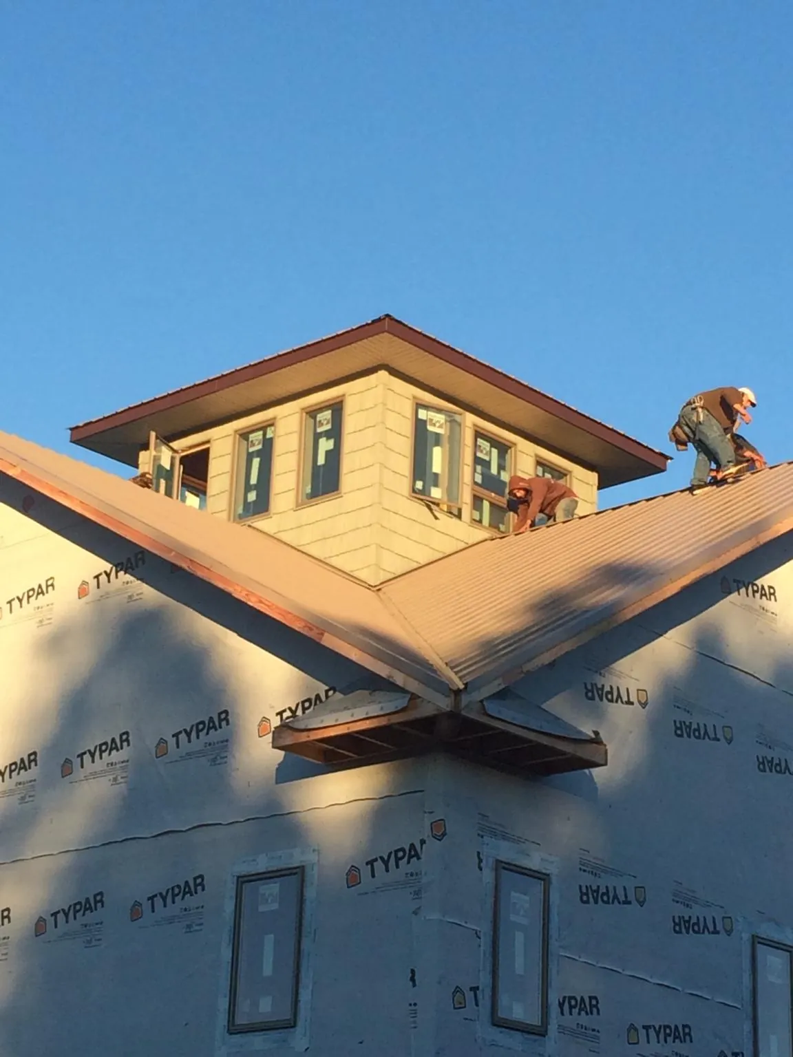 Roofers working around a rooftop cupola on a new metal roof at sunset — Roof Waterproofing in Lesterville by Roofing Brothers